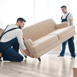 Delivery men moving sofa in room at new home